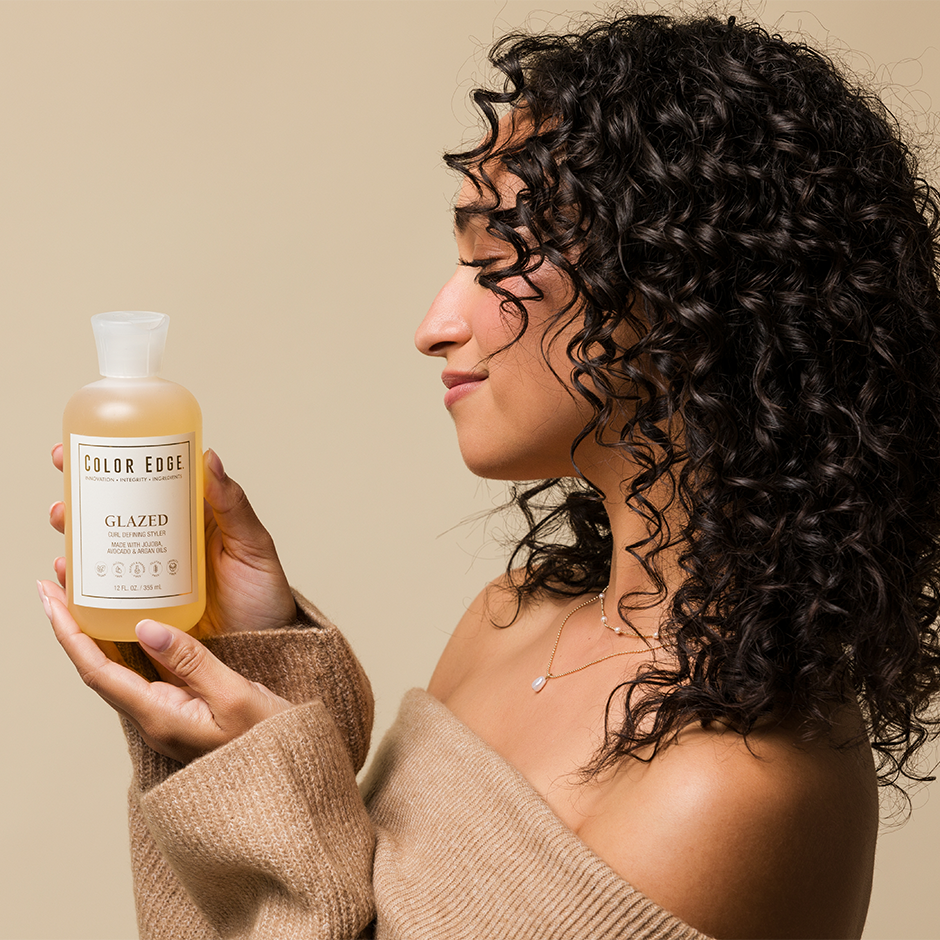Woman with curly hair holding a bottle of Glazed